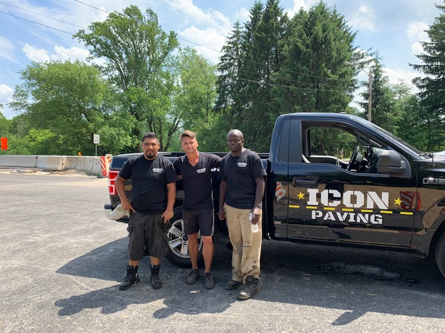 Icon Paving team standing with a branded company truck at a paving job site