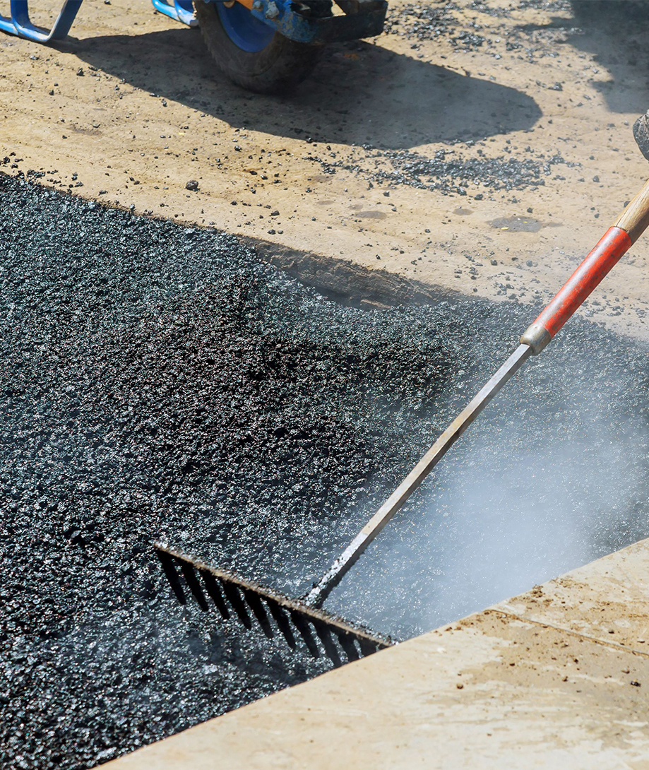 Worker raking asphalt during paving
